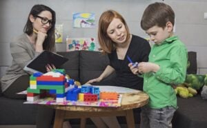 Child development specialist watching a child play with blocks